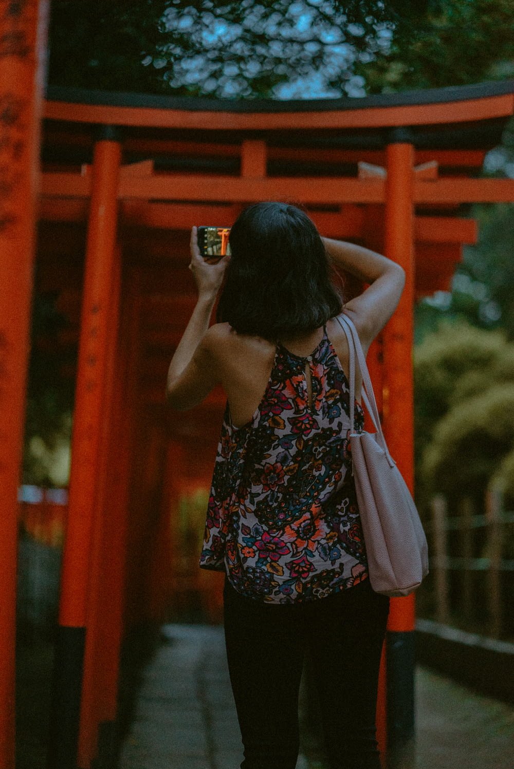 woman taking a picture of line of torii gates