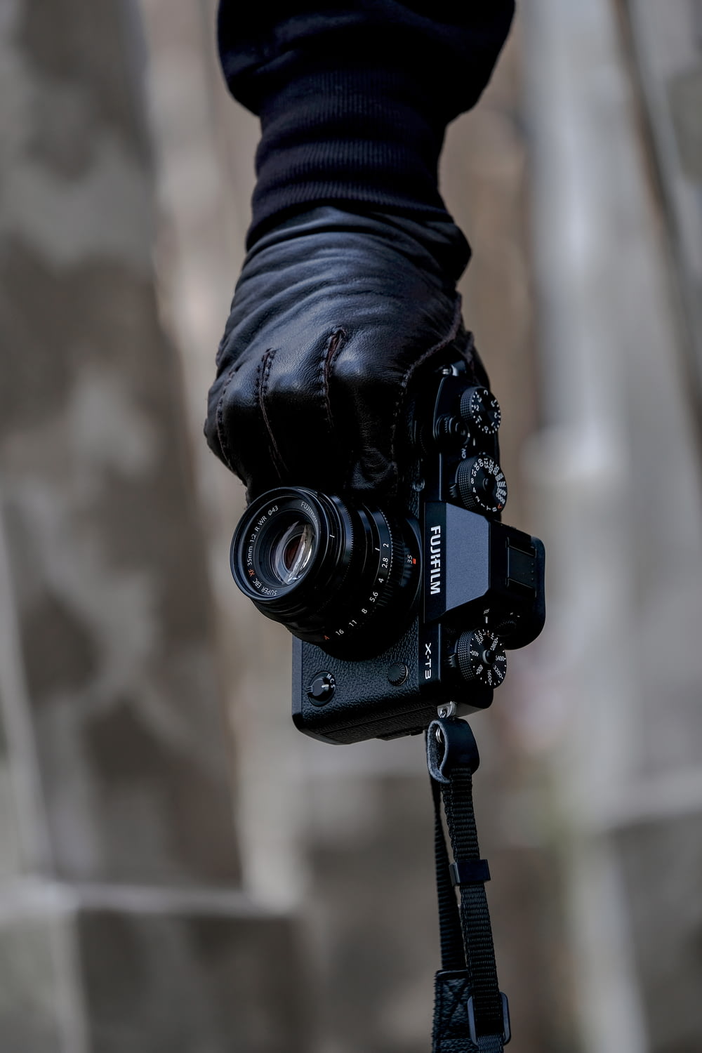 person's hand holding black Fujifilm bridge camera