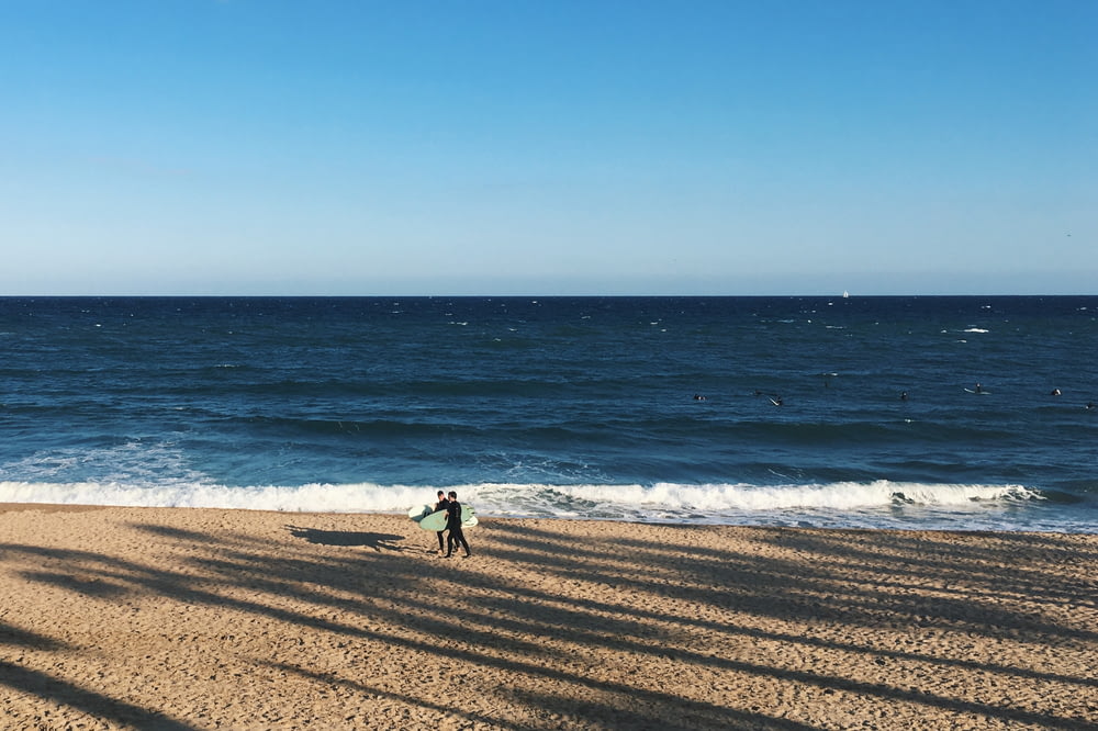 person walking beside seashore during daytime