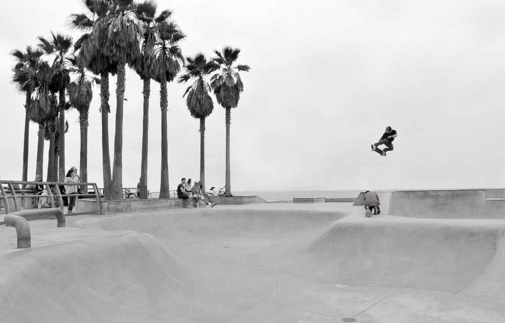 Photographie en niveaux de gris d’une personne faisant du skateboard et regardant les gens
