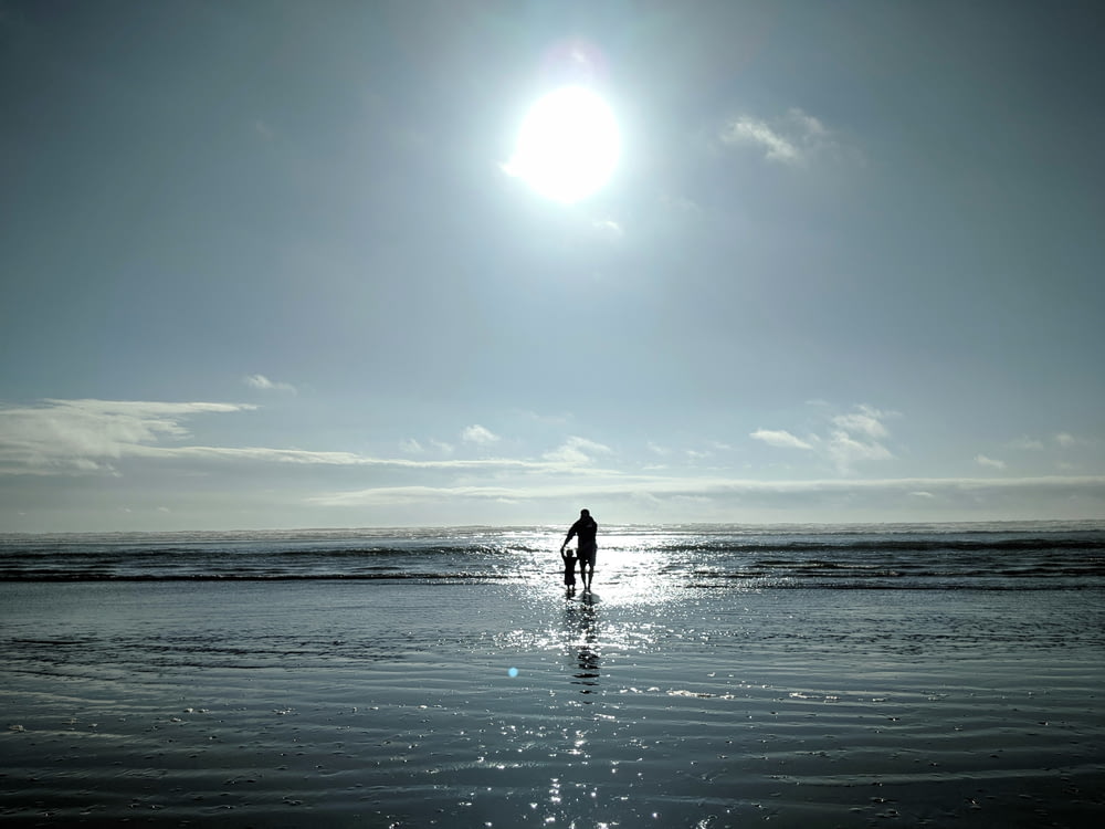 Homem e criança caminhando à beira-mar