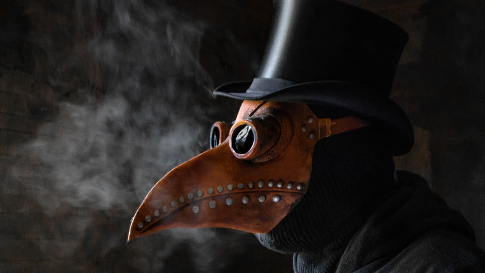 a man wearing a plague mask and a top hat