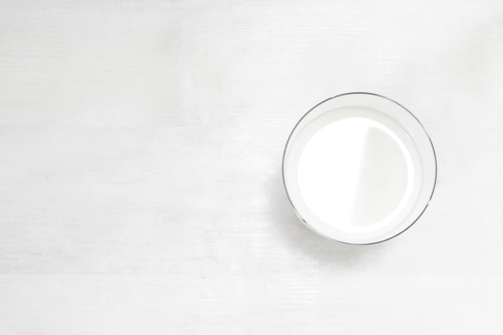 a glass of milk sitting on top of a white table