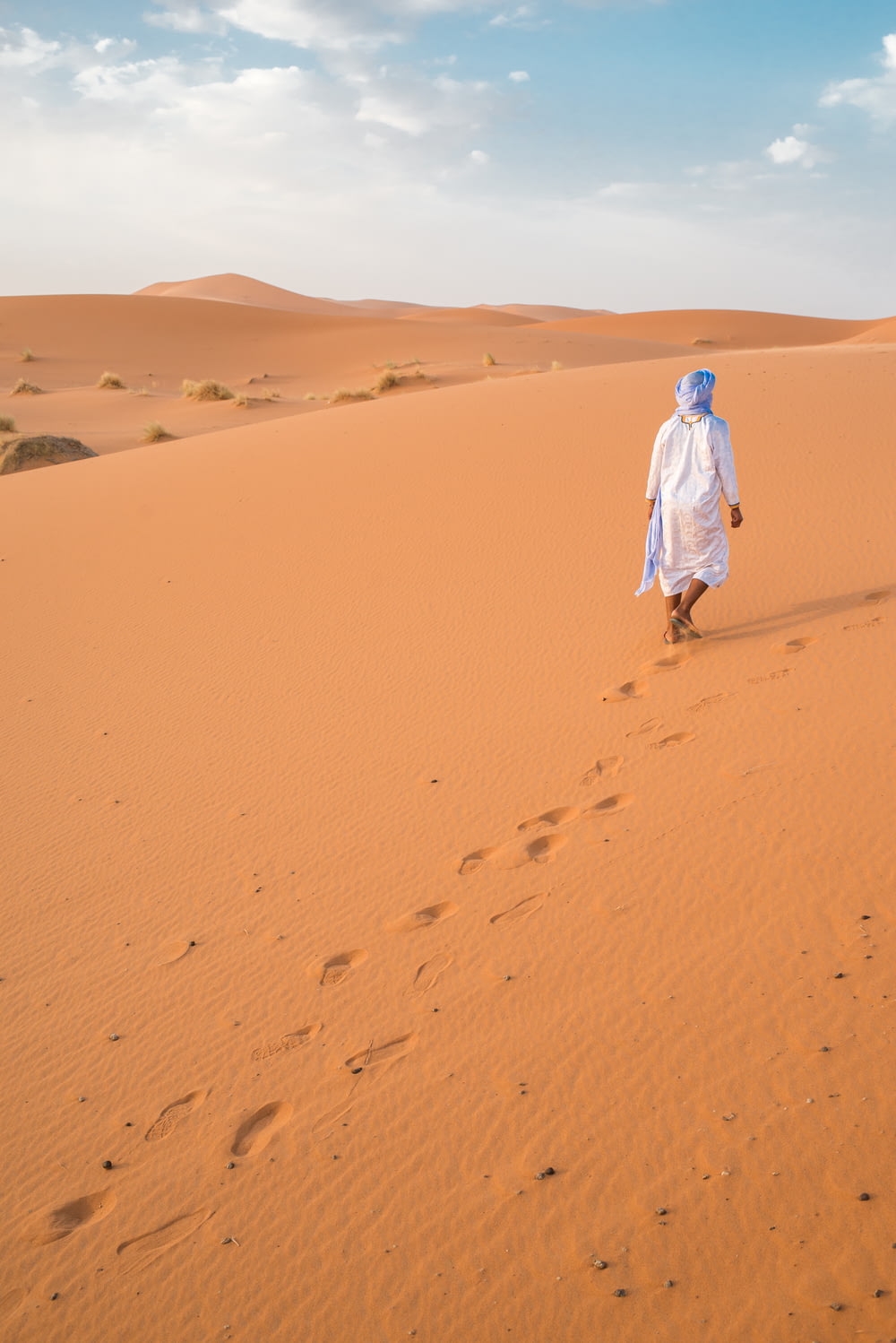 homem andando no deserto durante o dia