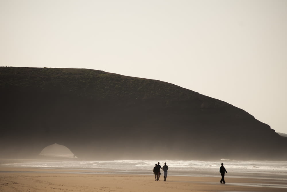 three person standing near ocean