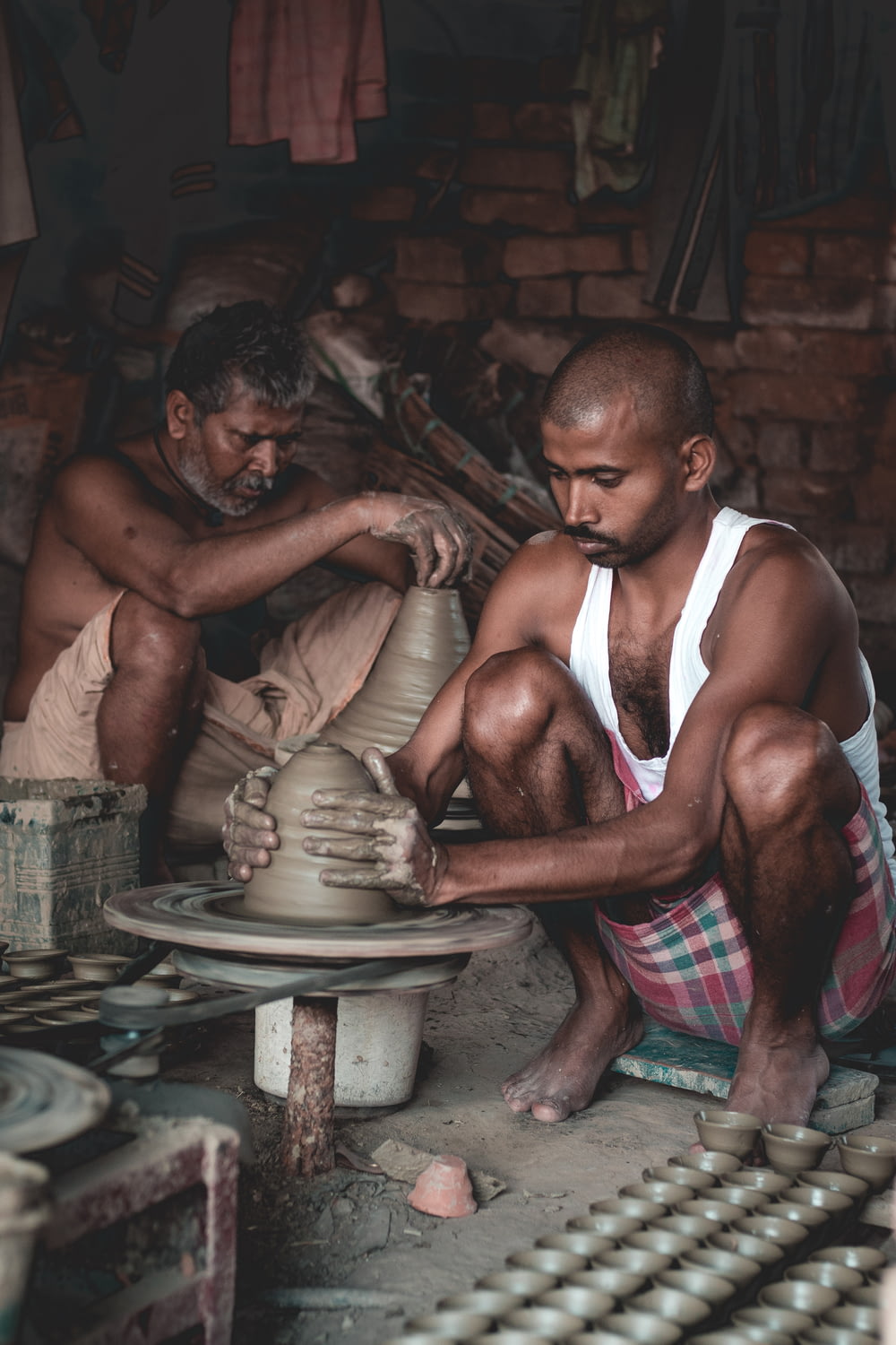 two men are working on a pottery wheel
