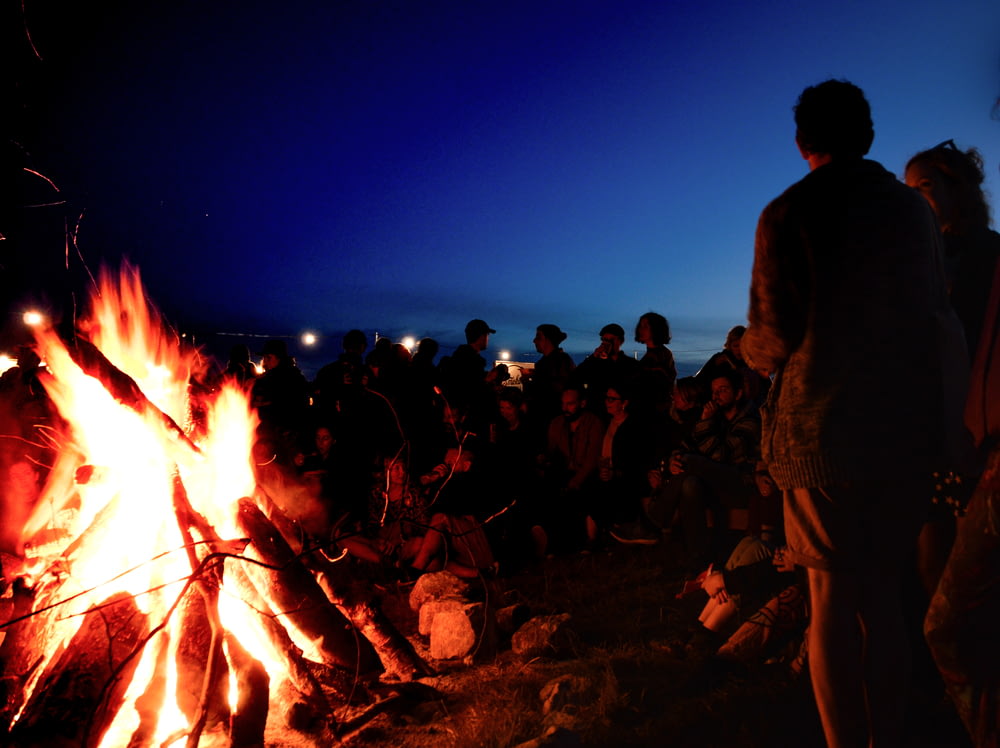 Pessoas se reúnem perto da fogueira durante a noite