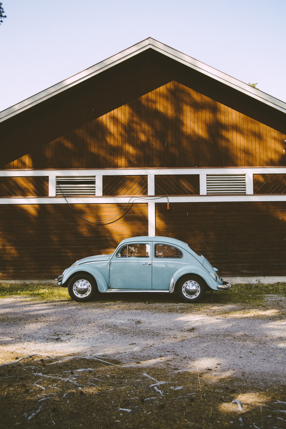 blue Volkswagen Beetle coupe beside wooden house