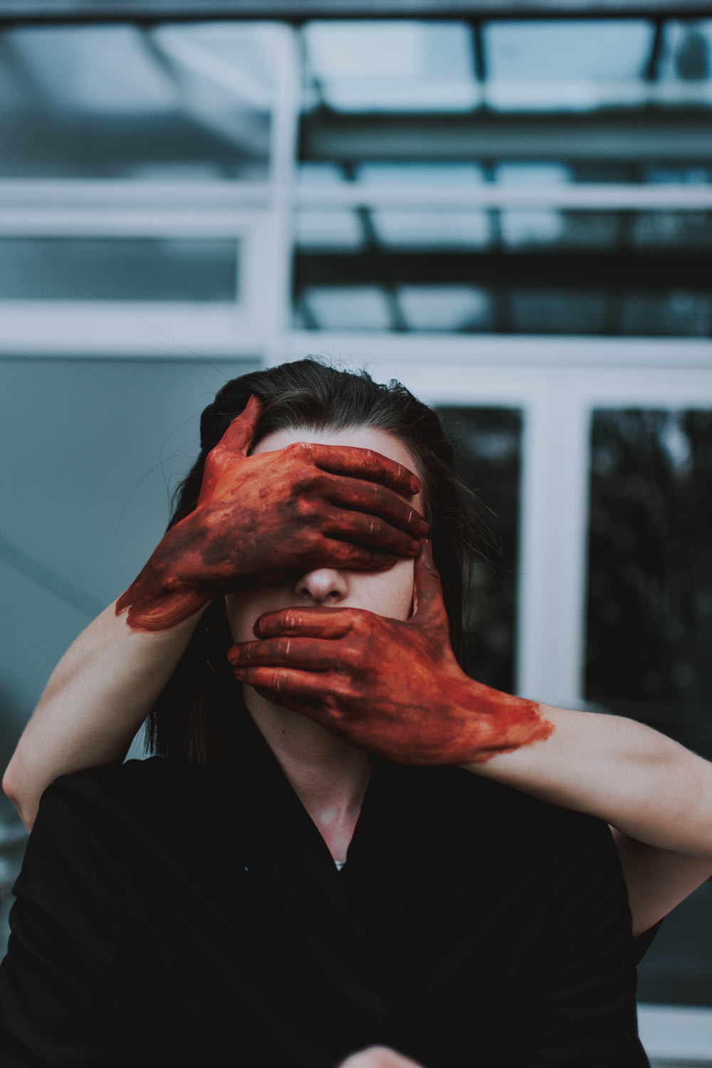 red painted hands holding woman's face