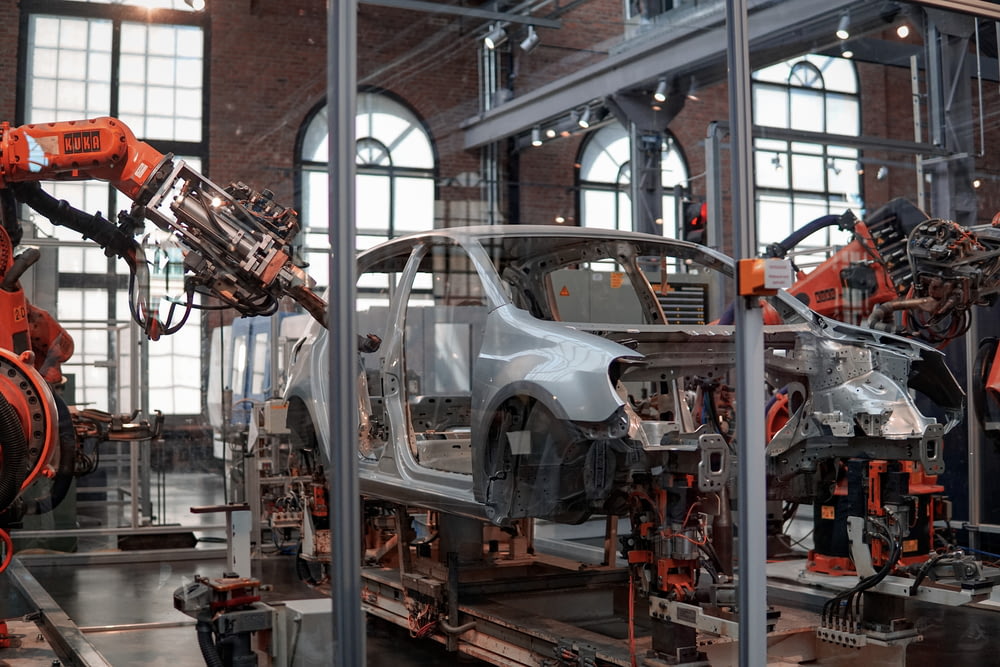 véhicule gris en cours de fixation à l’intérieur de l’usine à l’aide de machines robotisées