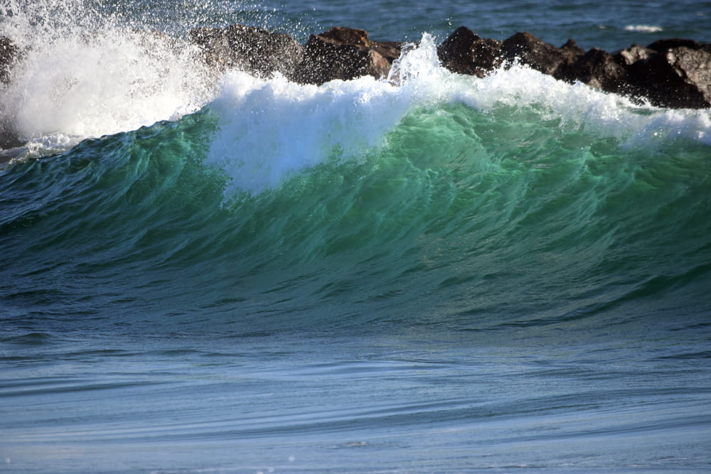 green sea wave near rock formations during daytime
