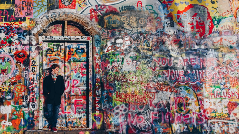 man standing front of graffiti wall