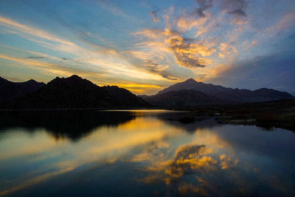 silhouette of mountain beside water during sunrise