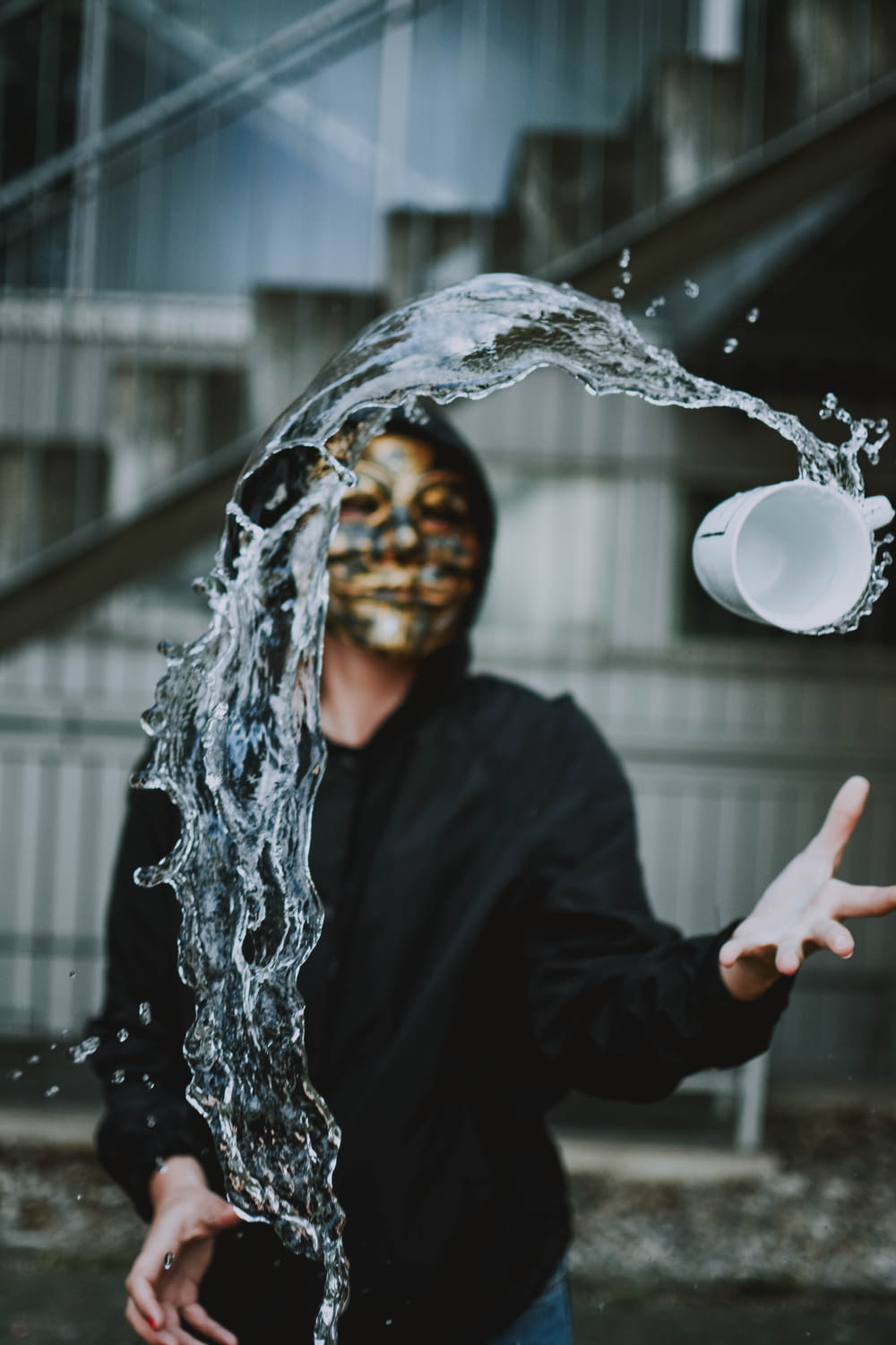 person with mask throwing mug with water