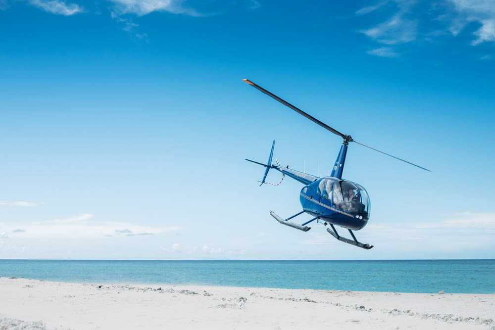 해변을 비행하는 파란 헬리콥터
