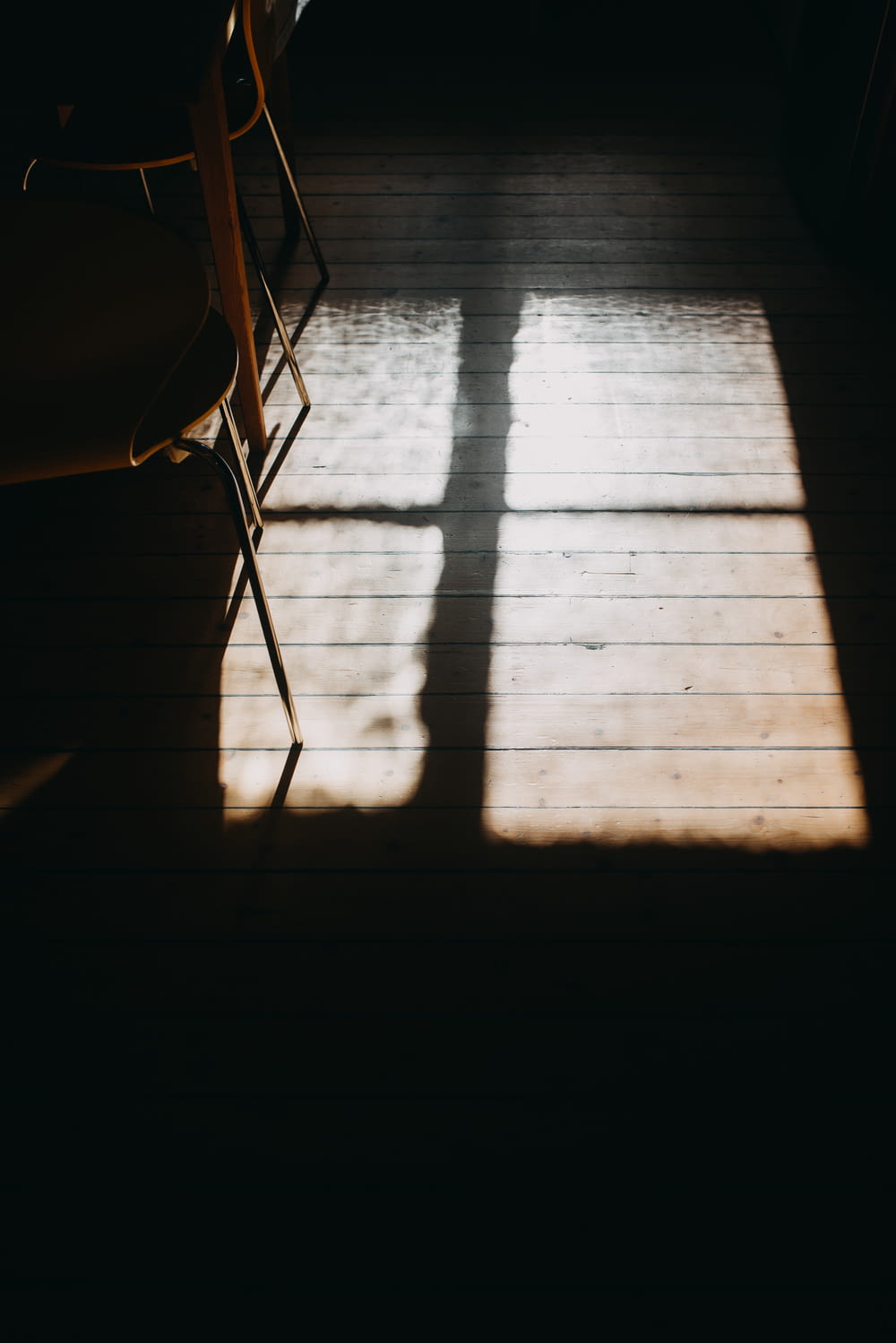 the shadow of two chairs on a wooden floor