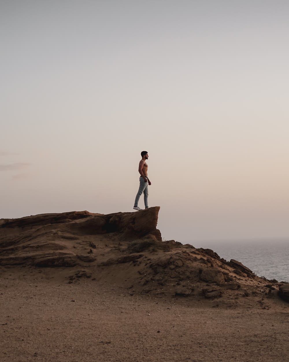 uomo in topless in piedi sulla collina rocciosa