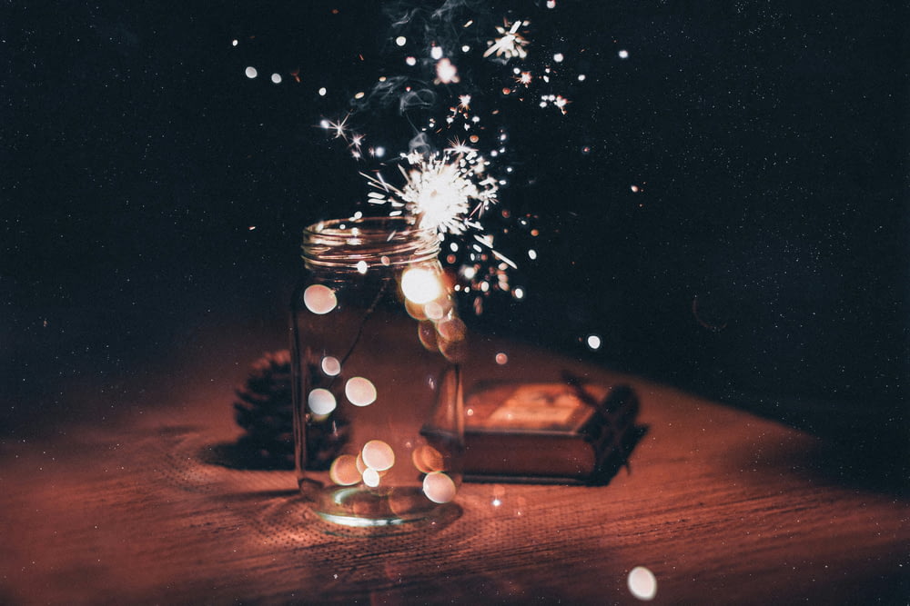 shallow focus photo of sparkler in clear glass jar