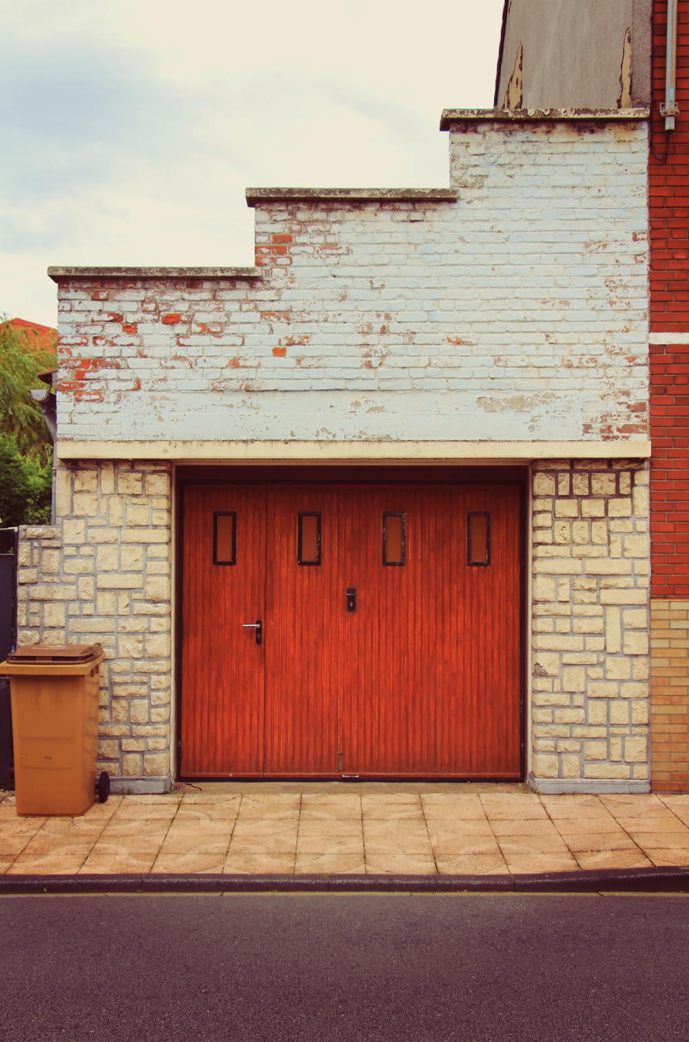 Un edificio di mattoni con una porta rossa e un bidone della spazzatura