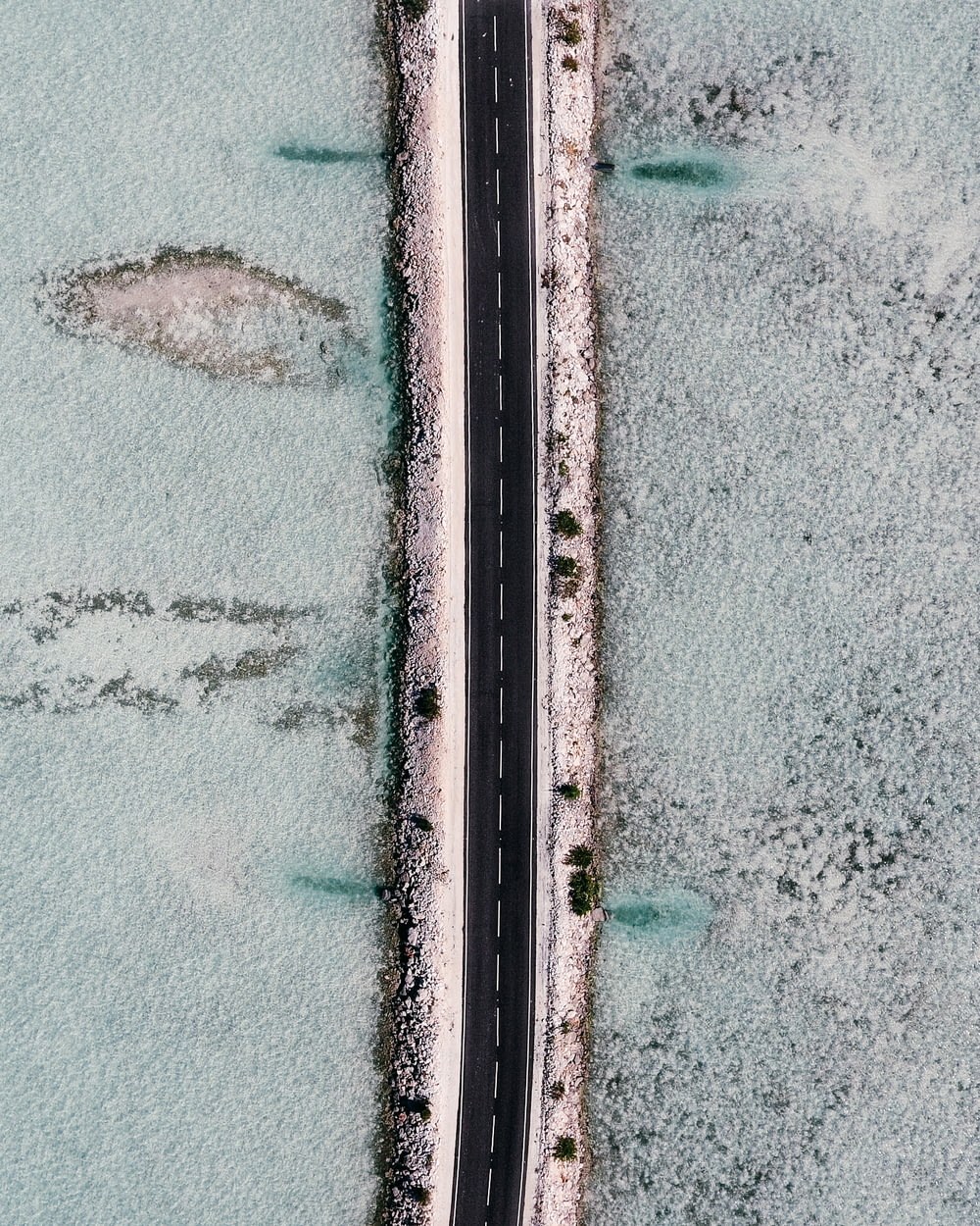 an aerial view of a road in the middle of a body of water