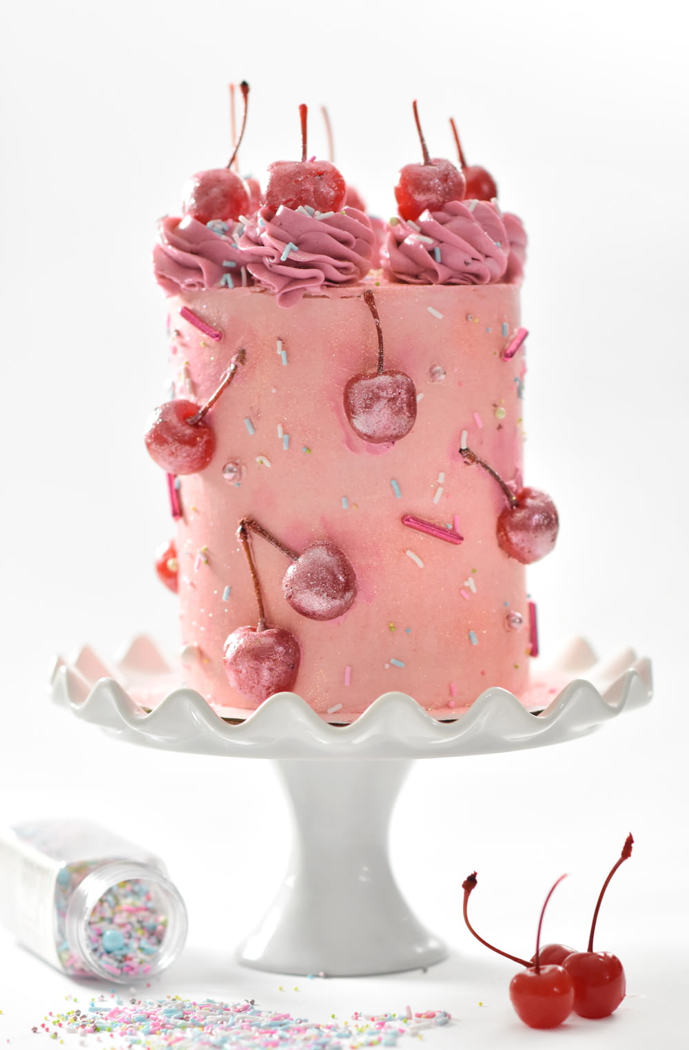 gâteau aux cerises roses sur plateau à gâteau sur pied blanc