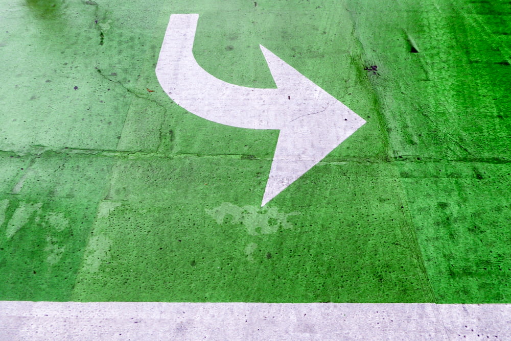 a white arrow painted on a green parking lot