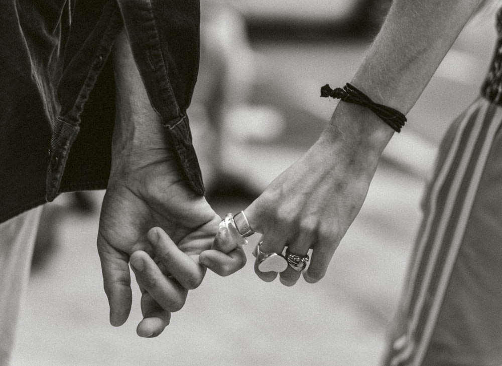 fotografia em tons de cinza do casal de mãos dadas enquanto caminha