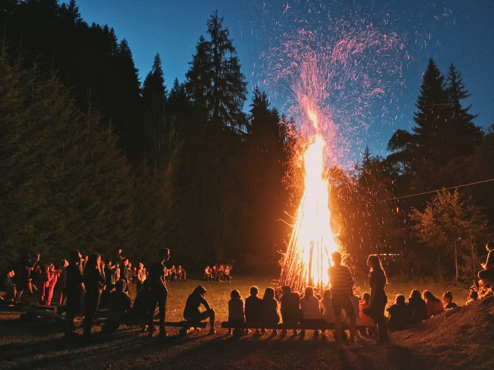 Fotografía time-lapse de una hoguera encendida rodeada de gente en un campamento