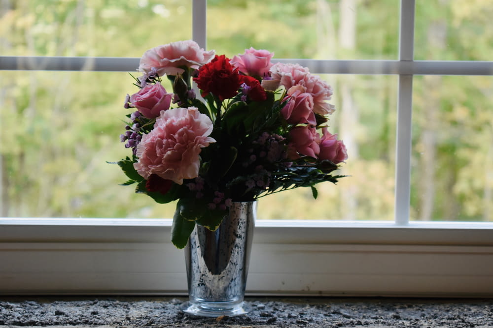 eine Vase mit Blumen, die auf einem Fensterbrett sitzt