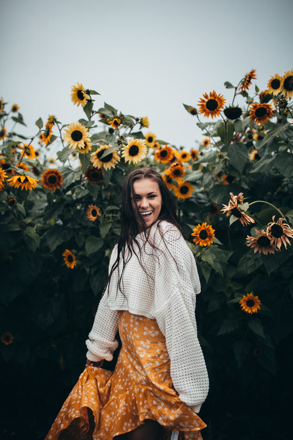 smiling woman standing beside black-eyed Susan flower field during daytime