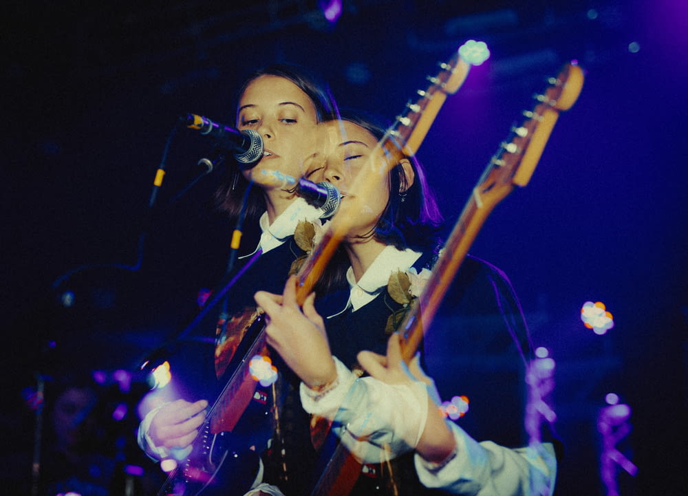 woman playing electric guitar while singing on stage