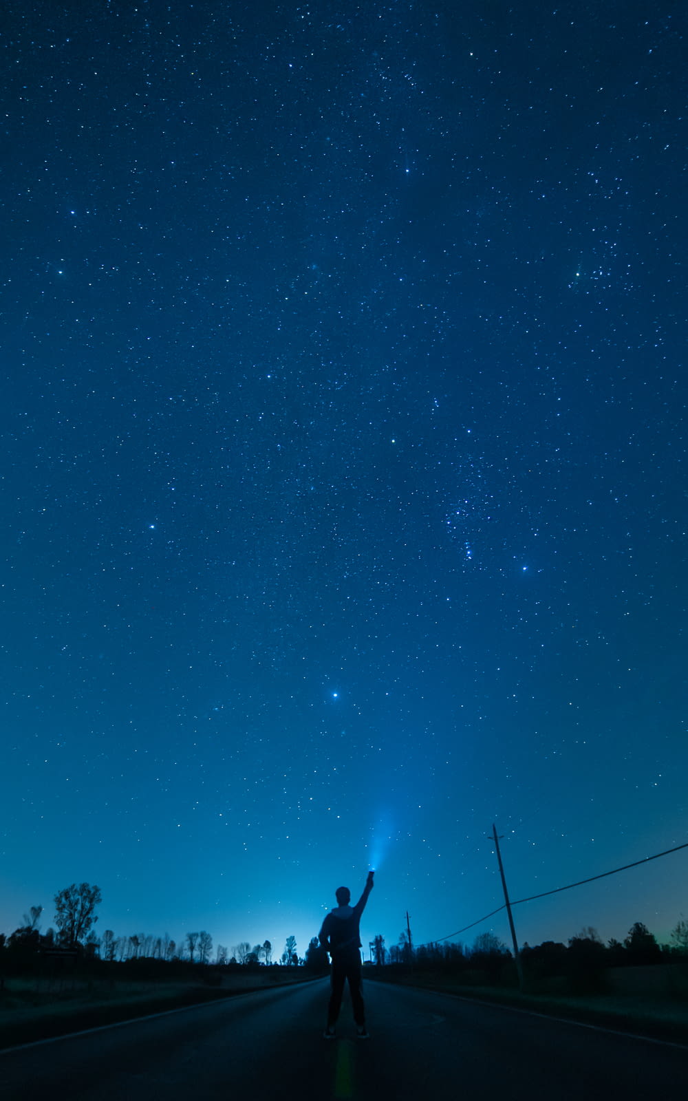 a man standing on the side of a road under a night sky
