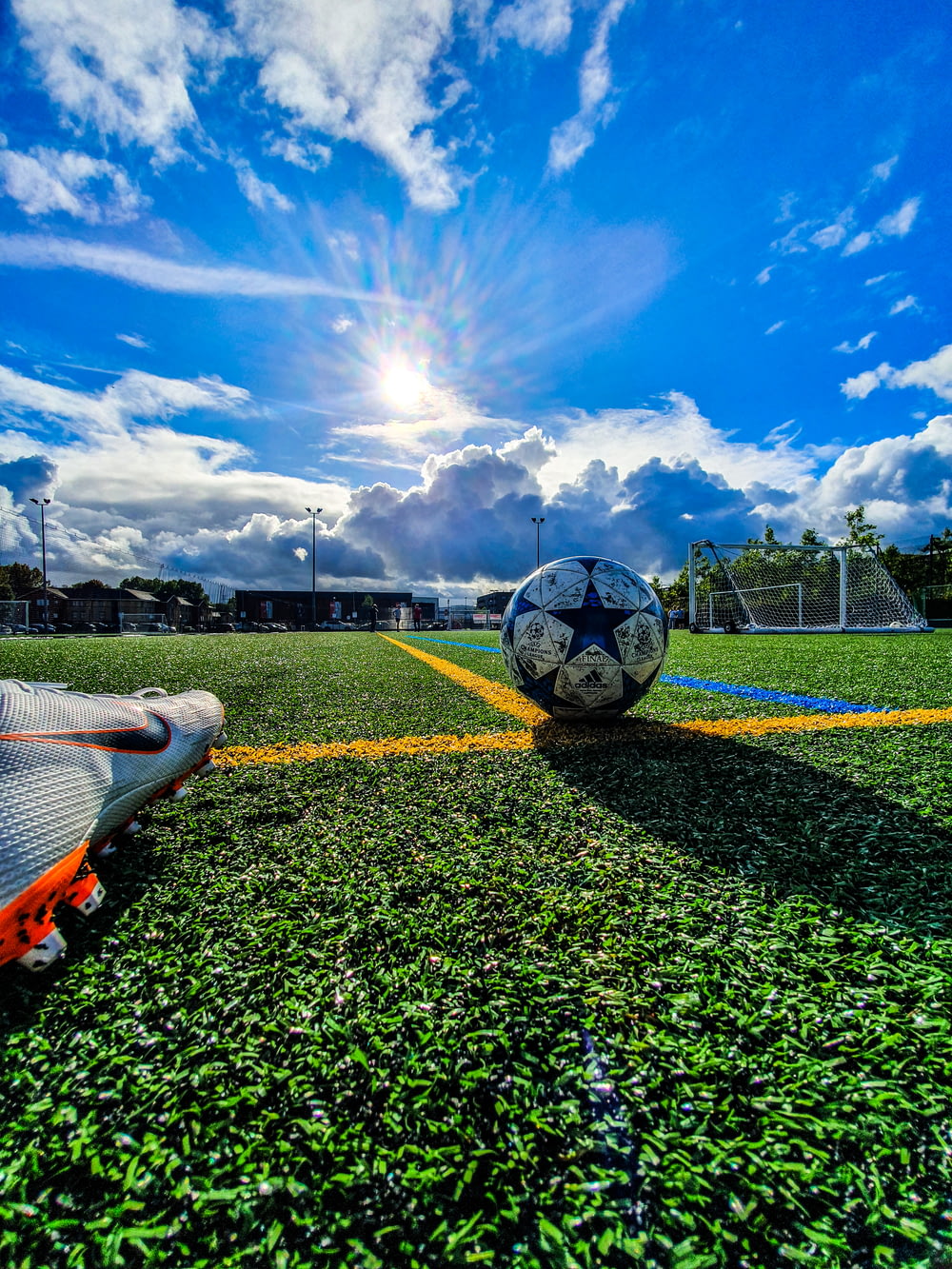 pallone da calcio blu e grigio sul campo verde sotto il cielo bianco e blu durante il giorno