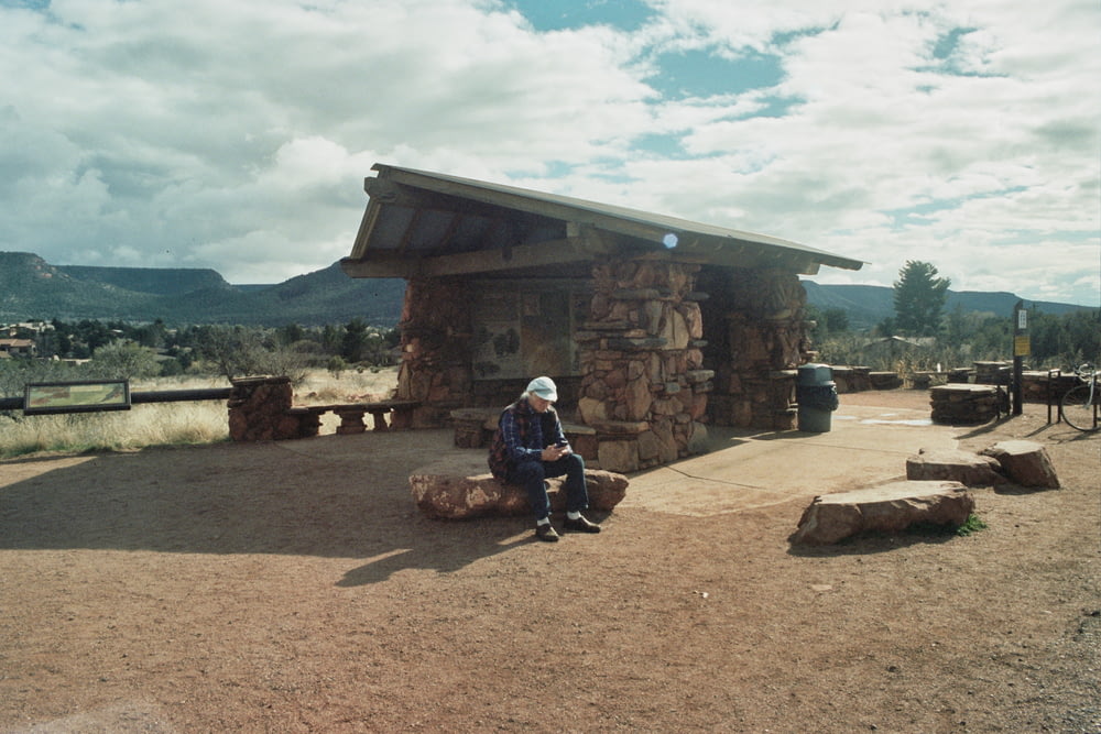 homem sentado em uma laje fora de uma casa de chalé