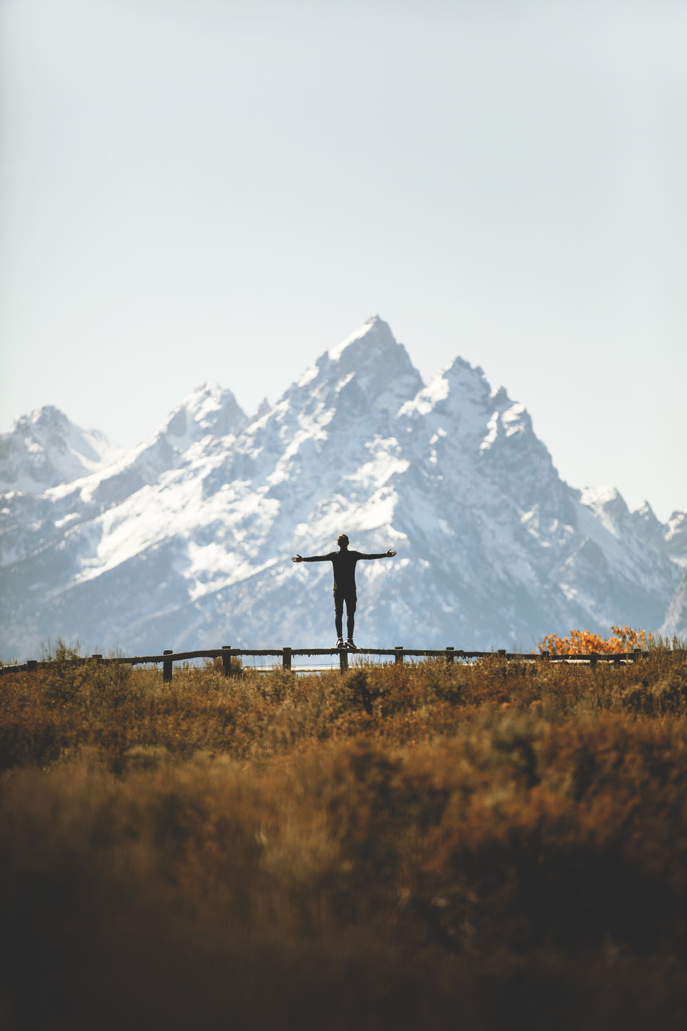 Mann steht auf Zaun mit Blick auf die Bergkette