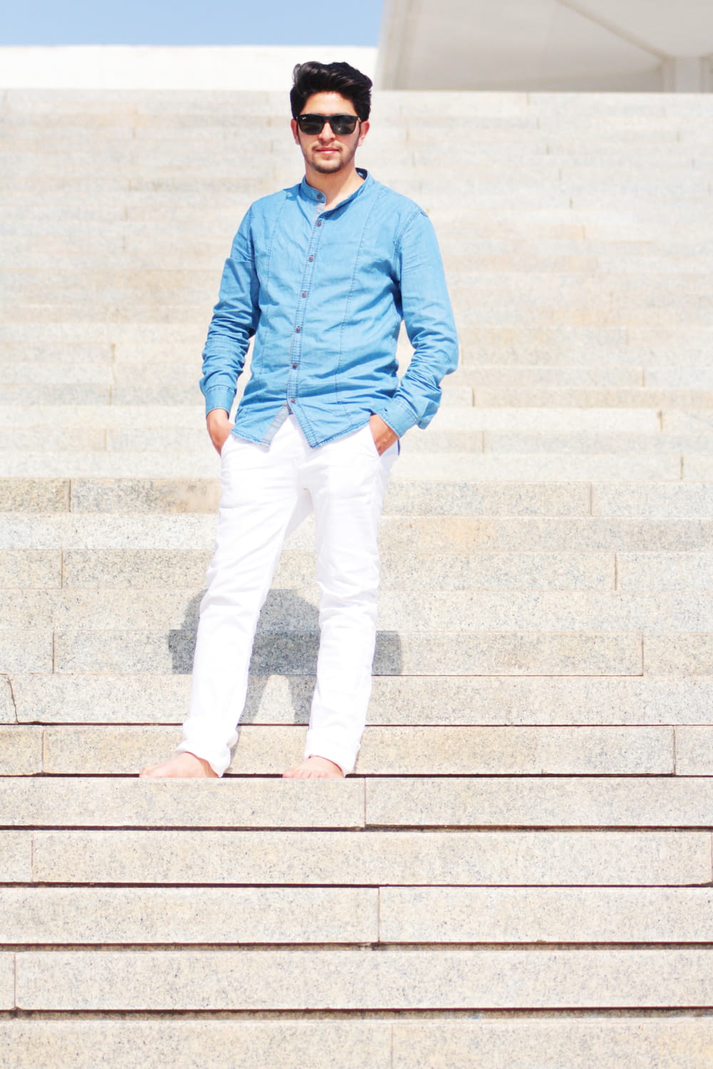 man wearing blue dress shirt and white jeans
