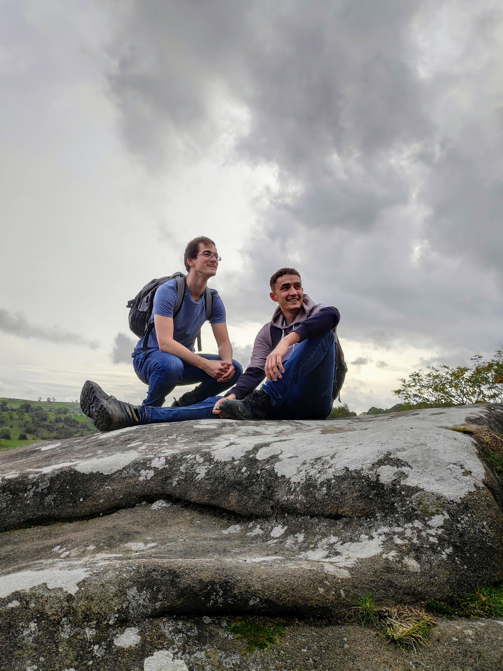 two men sitting on gray rock
