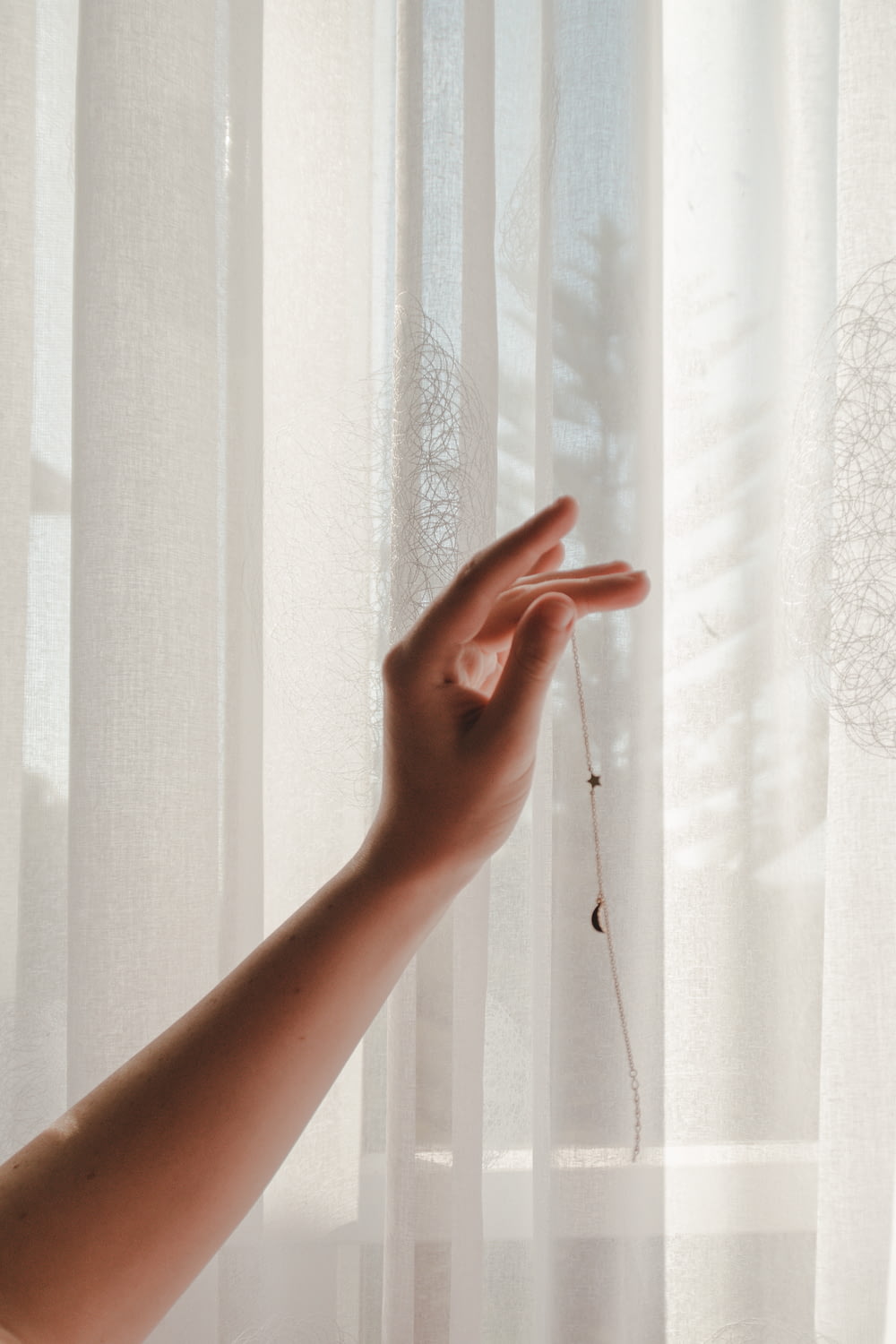 person holding window curtain during daytime