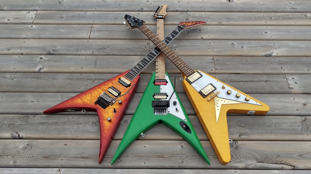 three assorted-color flying V electric guitars