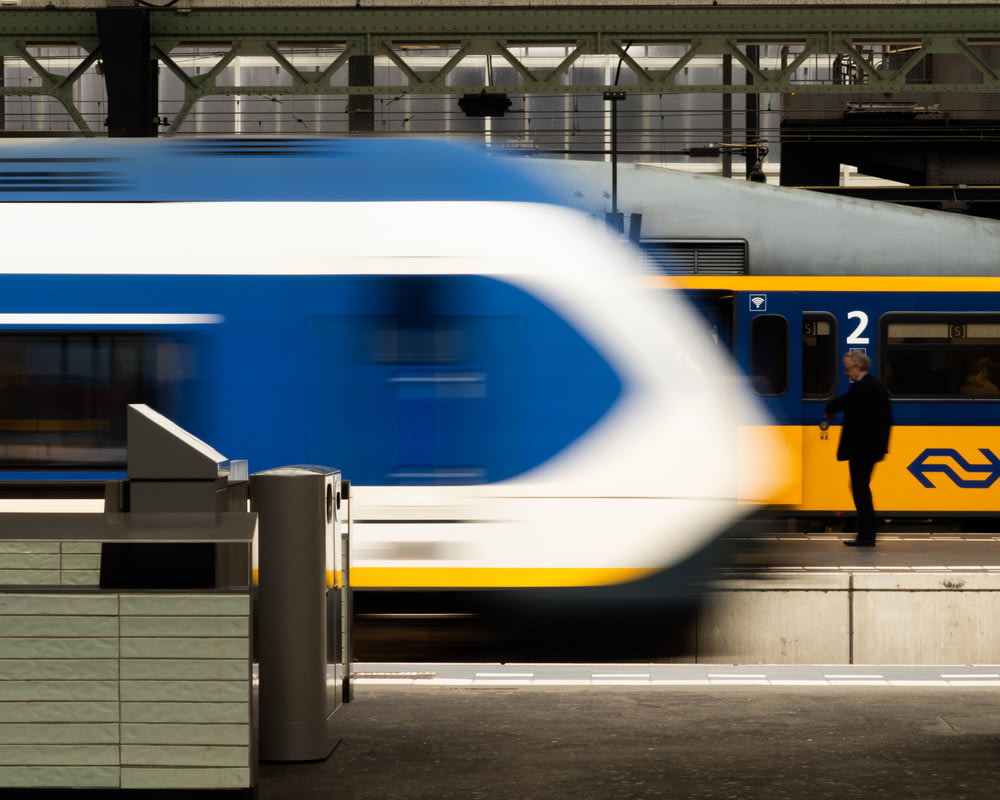 person standing near yellow and blue train
