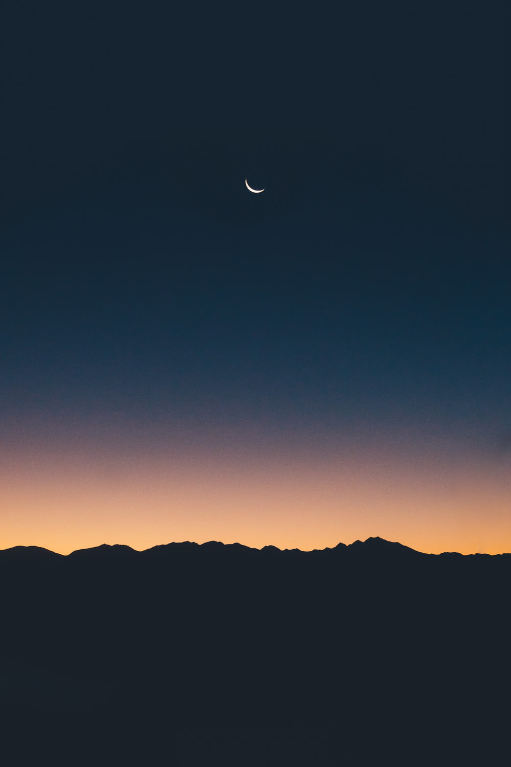 Silhouettenfotografie von Land unter einer Mondsichel während der goldenen Stunde