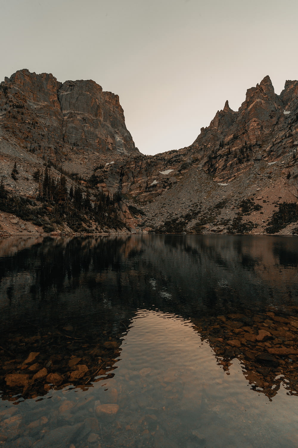 landscape photography of brown and black mountain ranges behind body of water
