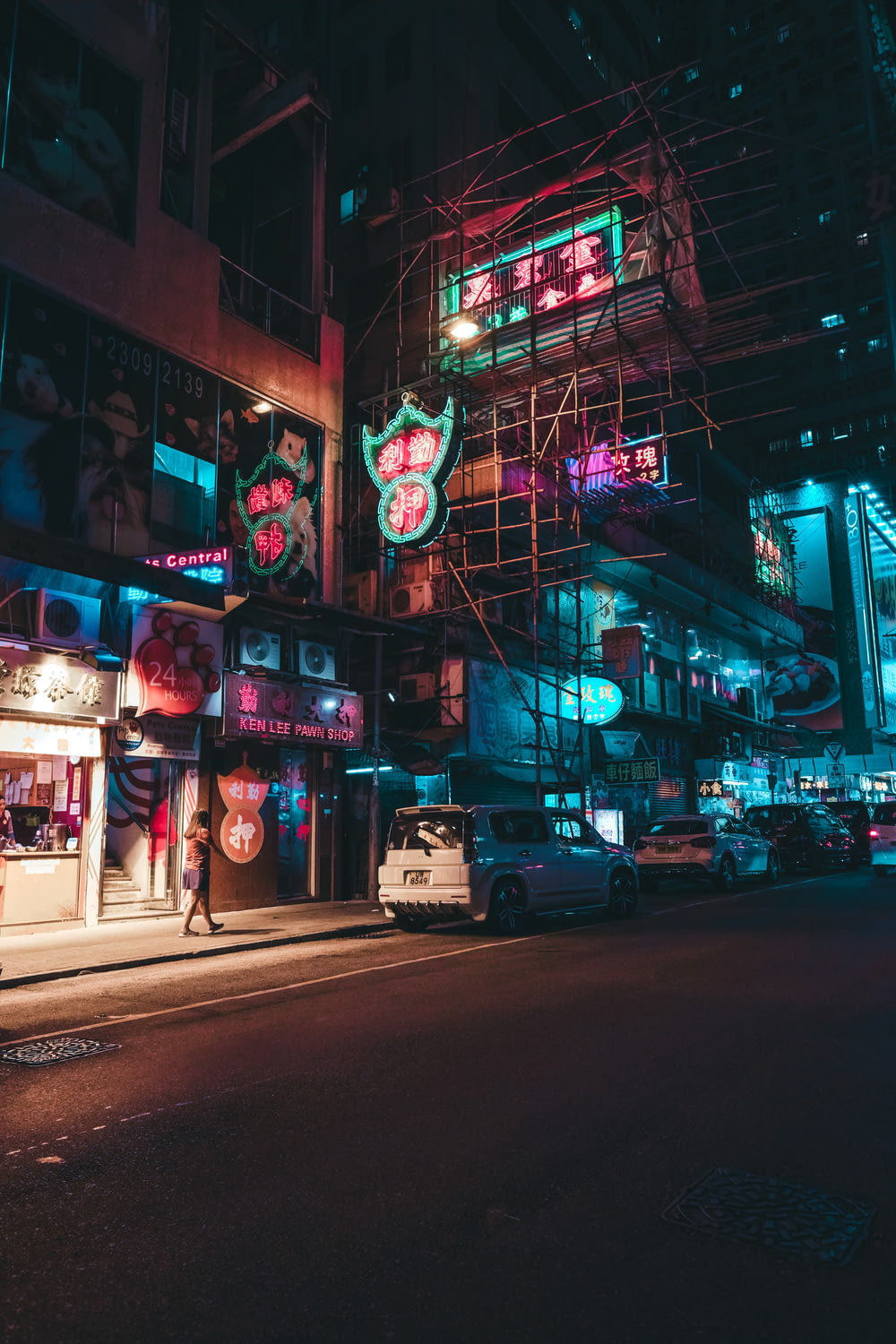 uma rua da cidade à noite com placas de néon e andaimes