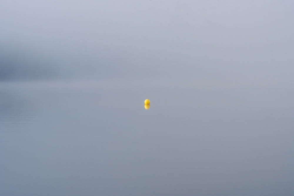 a yellow balloon floating in the middle of a body of water