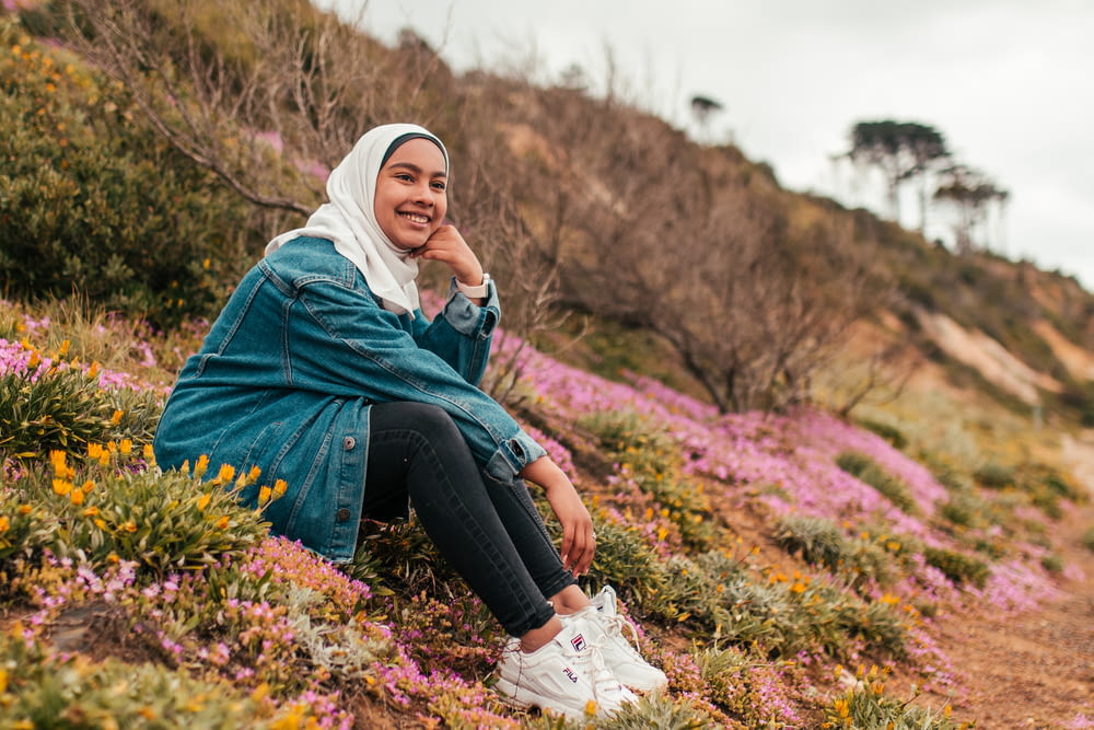 woman sitting on hill wearing gray denim jacket and white hijab scarf