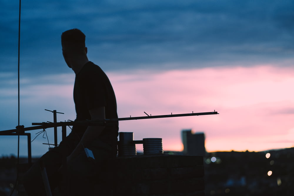 silhouette view of man sits on higher ground