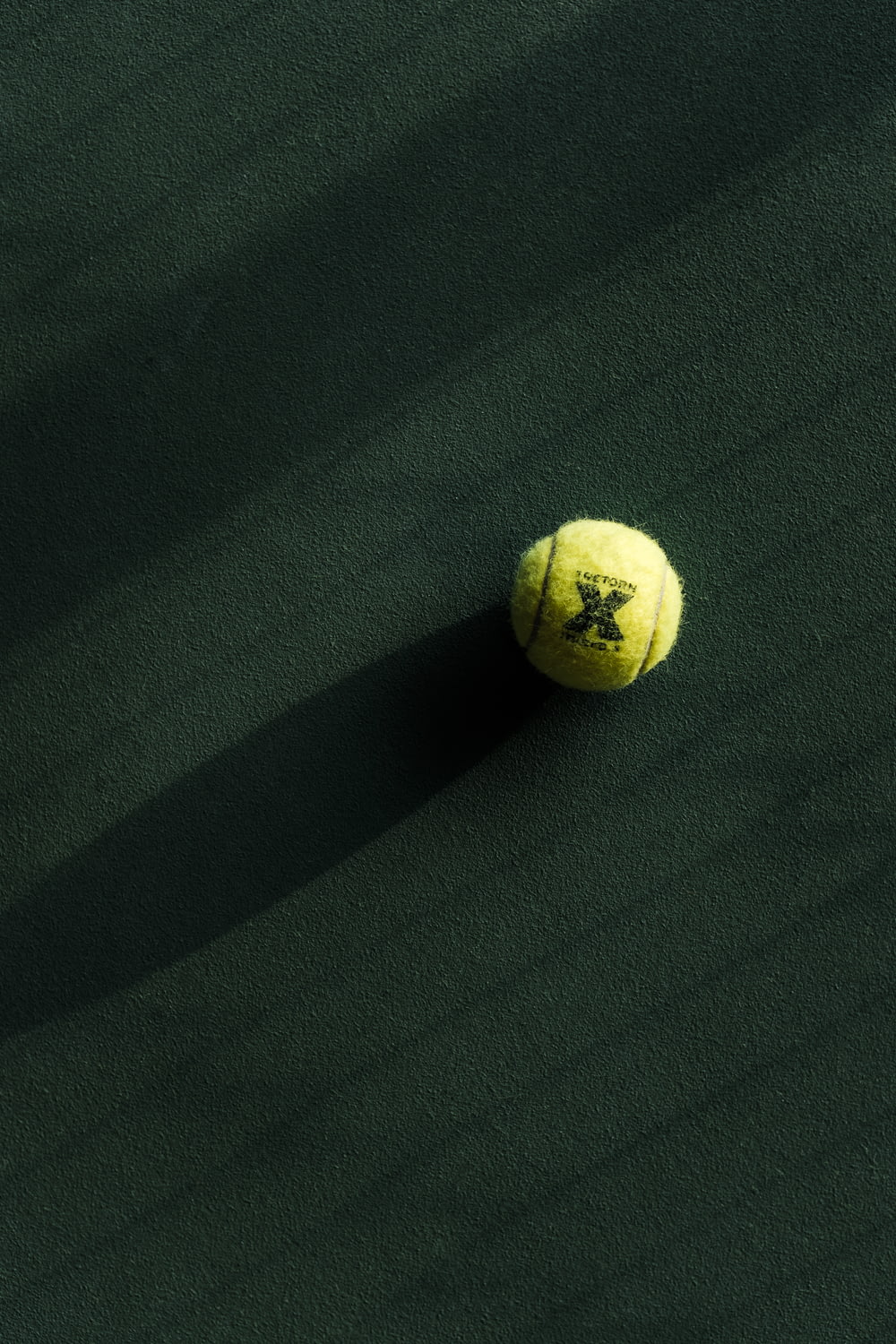 a tennis ball on a green court with a shadow