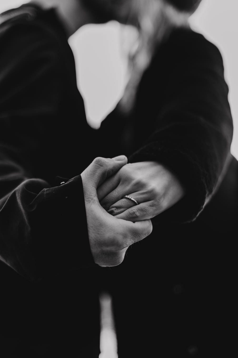 Photo en niveaux de gris d’un homme et d’une femme s’embrassant tout en se tenant la main