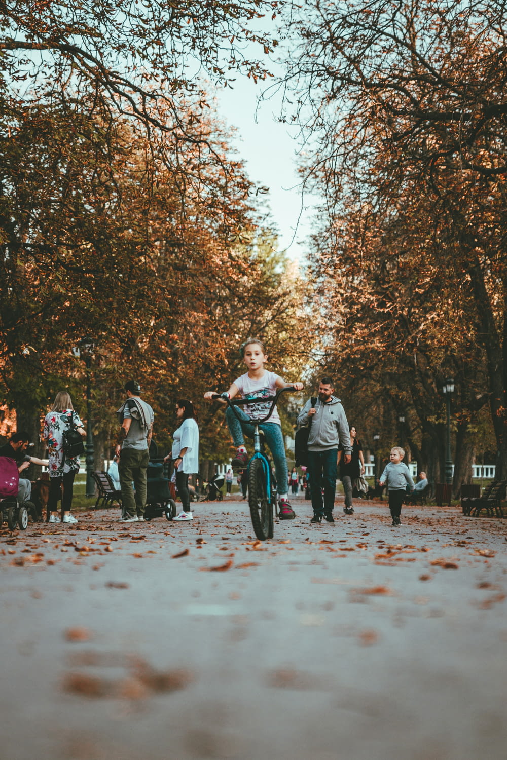 girl riding bicycle on pathway surrounded by people