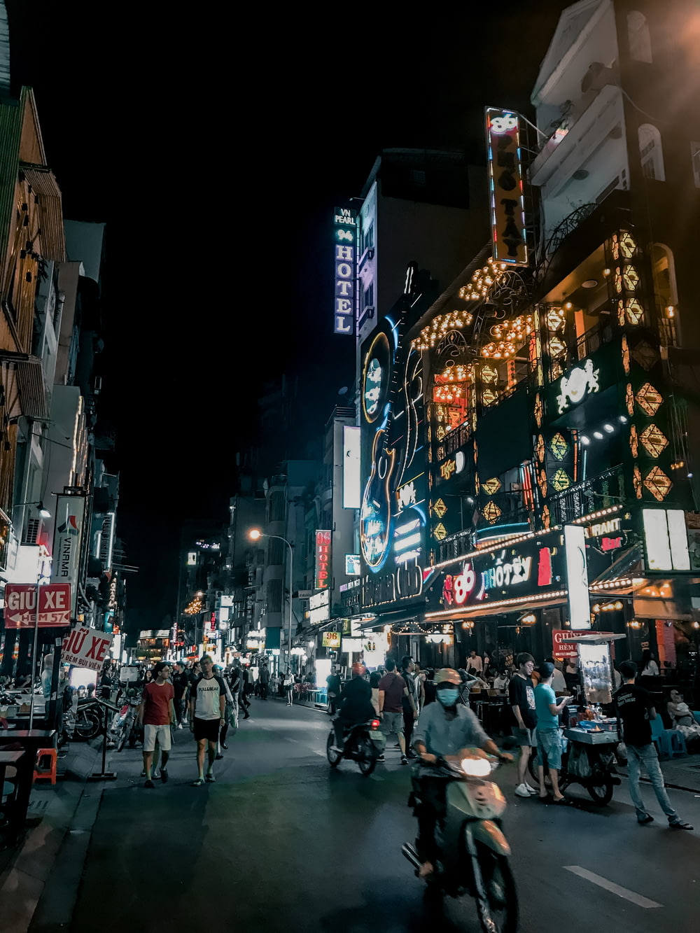 people walking on road between buildings during nighttime